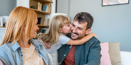 Une famille composée d’un père, d’une mère et de leur unique fille partageant un moment d’affection.