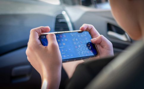 Un jeune en train de jouer sur son smartphone.