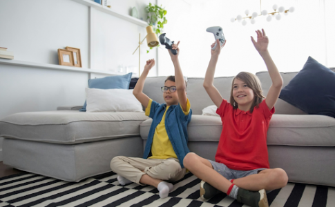Des jeunes garçons, manettes à la main, assis dans un salon et jouant à un jeu sur console.