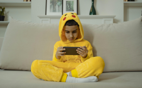 Un enfant assis jouant à son téléphone.