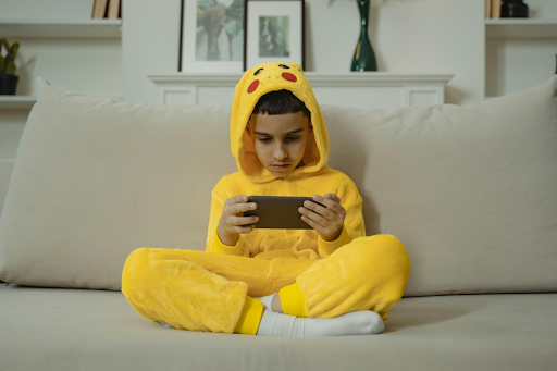 Un enfant assis jouant à son téléphone.