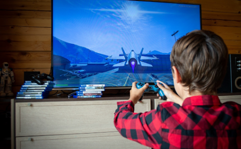 Un jeune garçon jouant à un jeu vidéo d’aviation sur sa console de salon.