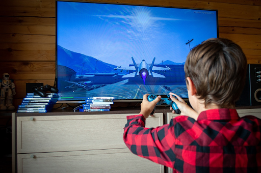 Un jeune garçon jouant à un jeu vidéo d’aviation sur sa console de salon.