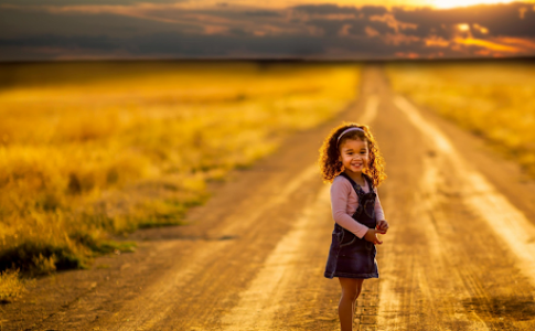 Une fille souriante au milieu de la route.