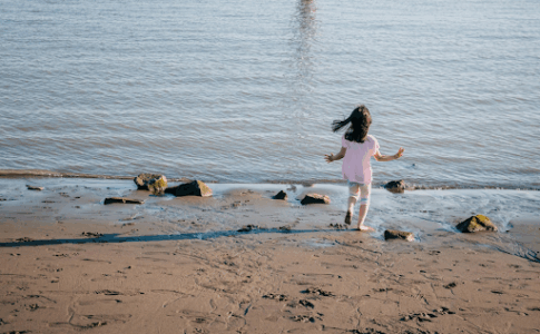 Jeune fille marche sur un sable de plage.
