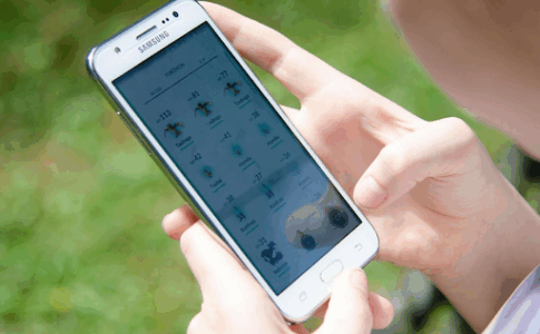 Un jeune garçon en train de consulter la liste des monstres du jeu Pokémon GO sur son smartphone.