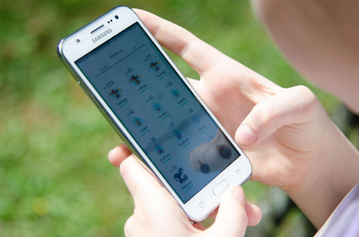 Un jeune garçon en train de consulter la liste des monstres du jeu Pokémon GO sur son smartphone.