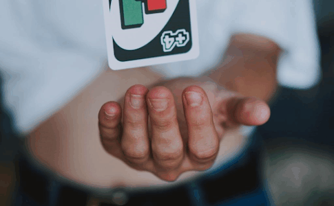 Une cartr UNO 4+ flottant au-dessus de la main d’un homme.