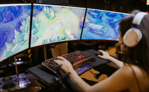 Une femme assise devant son écran jouant au jeu vidéo.