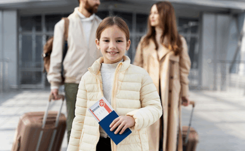 Une fillette tenant un ticket de voyage dans sa main avec ses parents à l’arrière, tirant des valises à roulettes.