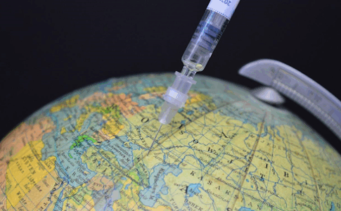 Une seringue de vaccin plantée dans un globe terrestre.