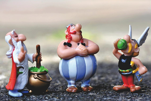 Des figurines d’Astérix, de Panoramix et d’Obélix posées sur le bitume.