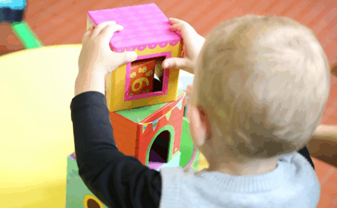 Un jeune bébé en train de jouer à des blocs de bois dans une crèche.