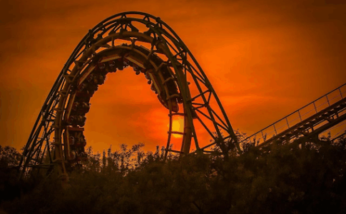 Un looping de montagne russe sous un soleil de couchant rougeoyant.