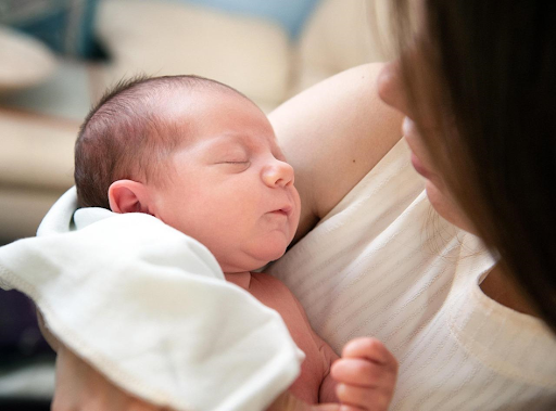 Un petit bébé endormi dans les bras de sa mère.