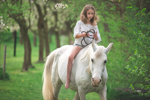Une jeune fille montant à cheval dans une petite clairière.