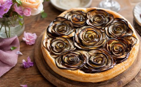 Une tarte salée surmontée de plusieurs rosaces d'aubergines grillées.