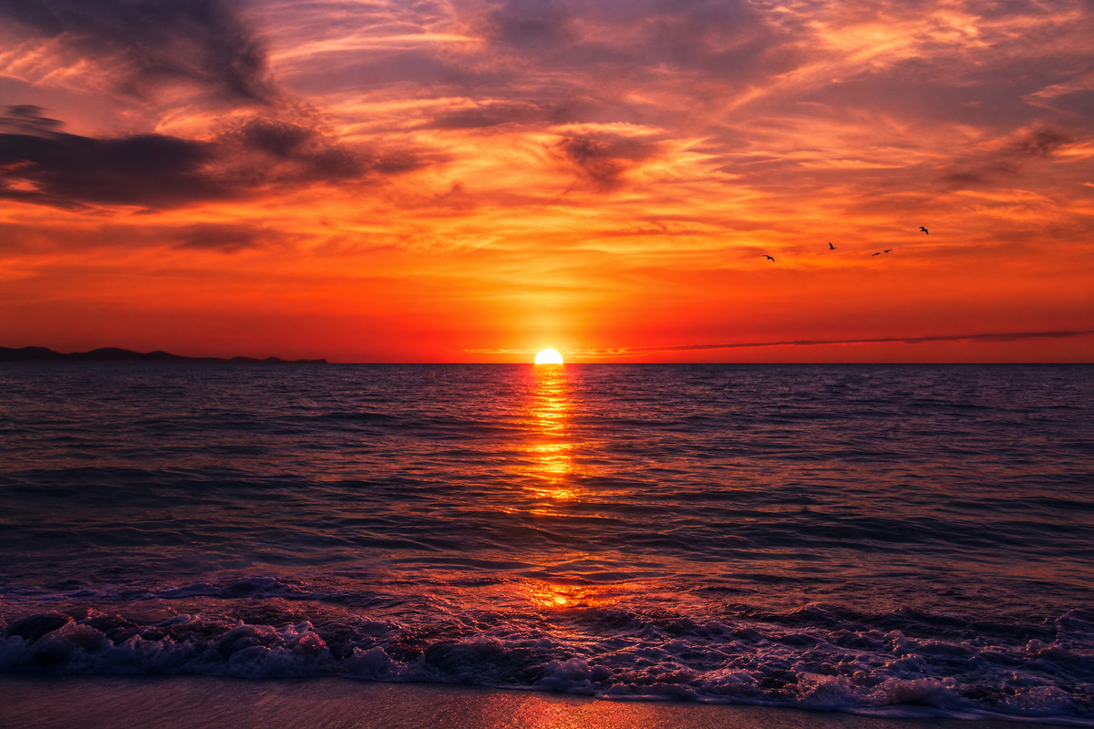 Un coucher de soleil flamboyant sur l'océan avec un ciel orange et rouge.