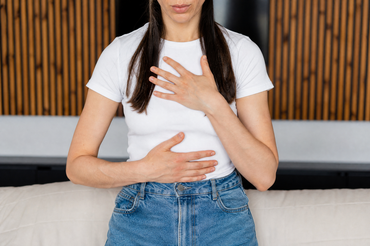 Femme avec les mains sur le corps, illustrant une crise d'angoisse. 