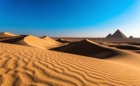 Désert africain avec pyramides lointaines et dunes dorées