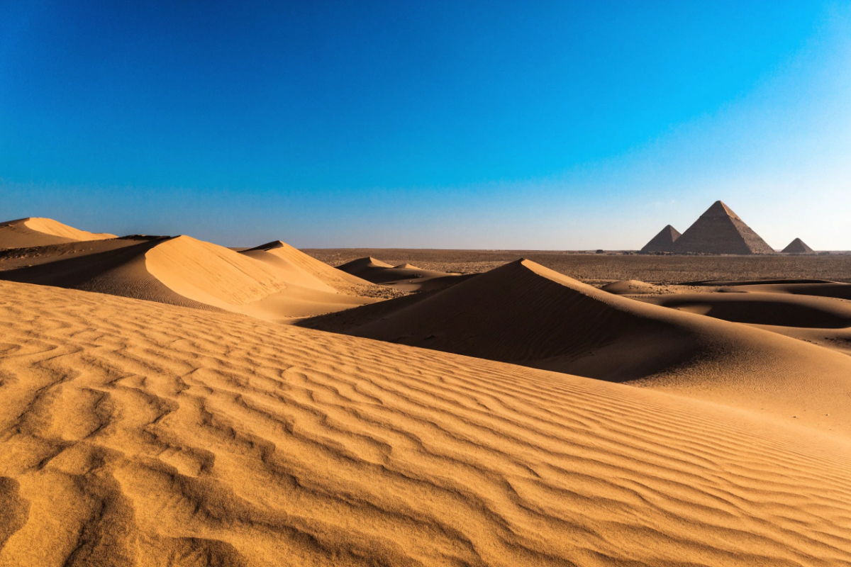 Désert africain avec pyramides lointaines et dunes dorées