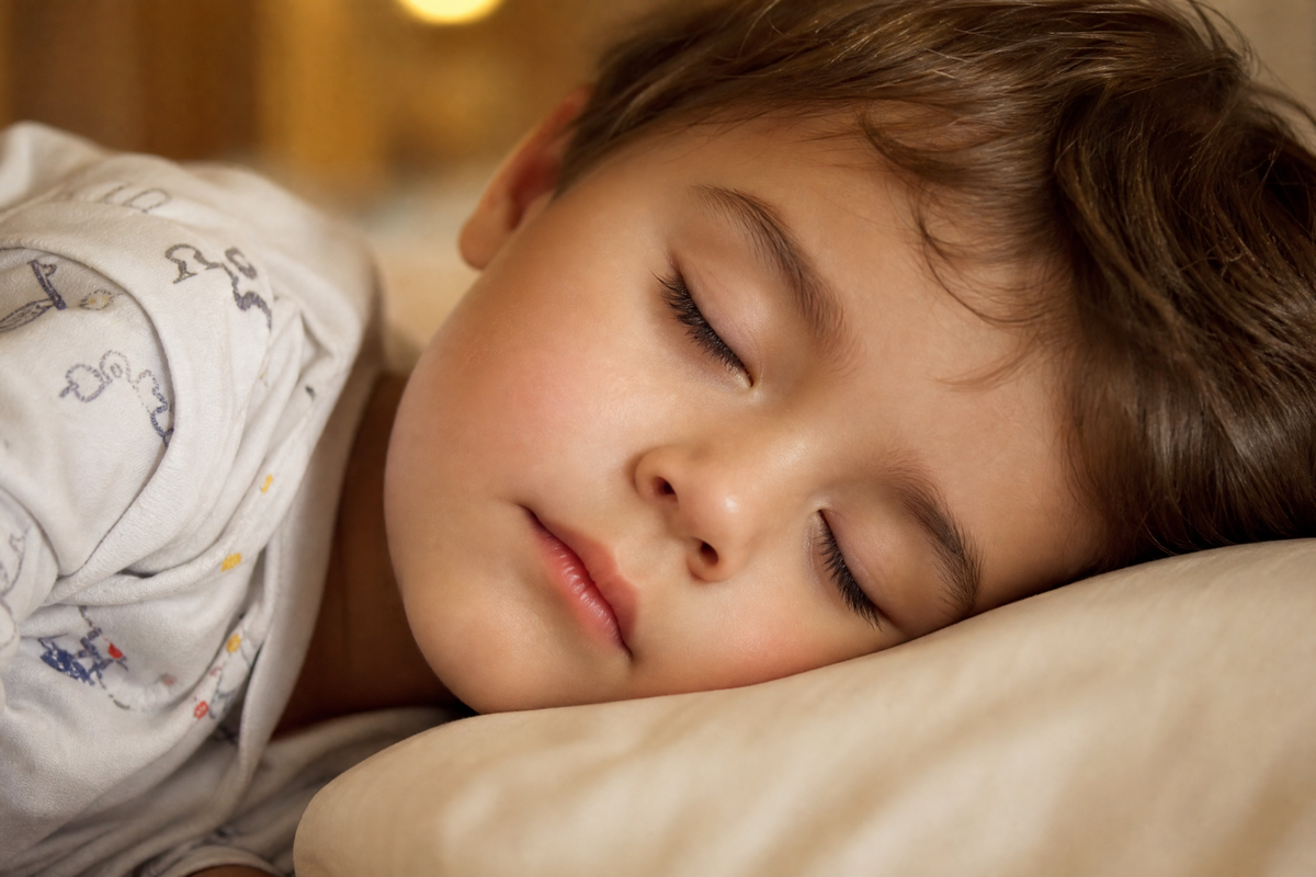  Un jeune enfant qui dort paisiblement la tête posée sur un oreiller blanc pendant l'été.