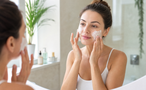 Une femme appliquant un produit de soin sur son visage.