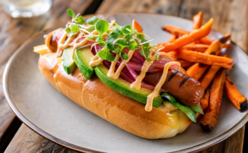 Hot-dog végétarien à l'avocat et frites de patate douce.
