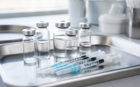 Flacons médicaux et seringues posés sur un plateau en inox.