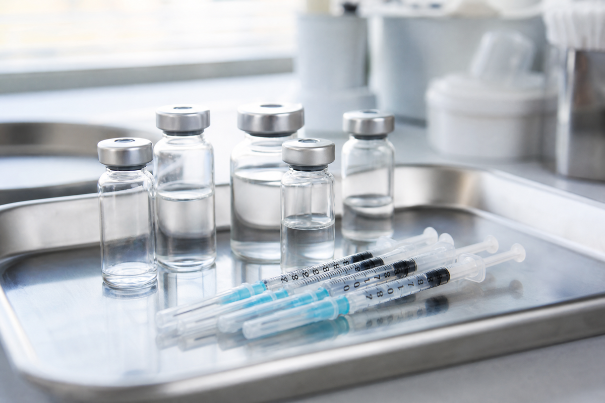 Flacons médicaux et seringues posés sur un plateau en inox.