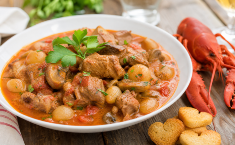 Sauté de veau Marengo servi dans une assiette creuse avec des champignons, des oignons grelots.
