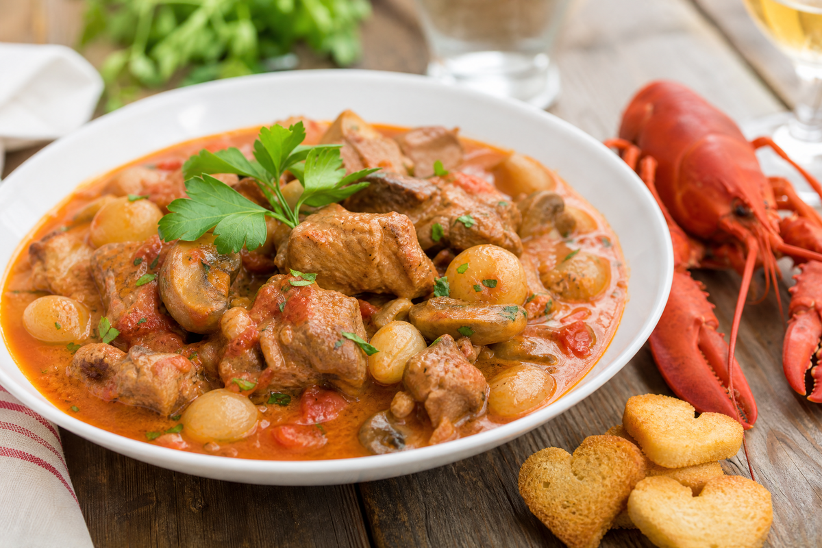 Sauté de veau Marengo servi dans une assiette creuse avec des champignons, des oignons grelots.