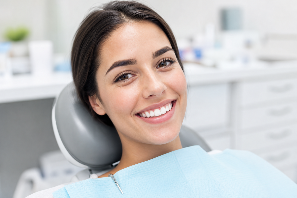 Une femme souriante affichant des dents blanches et saines dans un cabinet dentaire.