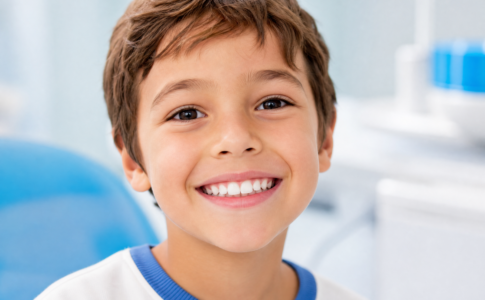 Un jeune garçon souriant avec des dents blanches et saines dans un cabinet dentaire.