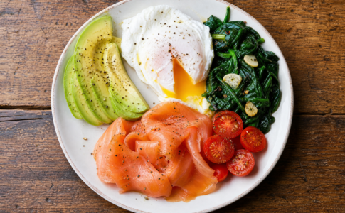 Assiette de petit-déjeuner équilibré avec œuf poché, saumon fumé, avocat, épinards et tomates cerises.