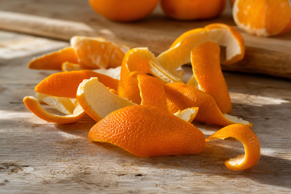 Écorces d'orange fraîches posées sur une table en bois rustique.