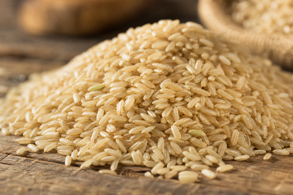 Des grains de riz brun entier présentés sur une surface en bois rustique. 